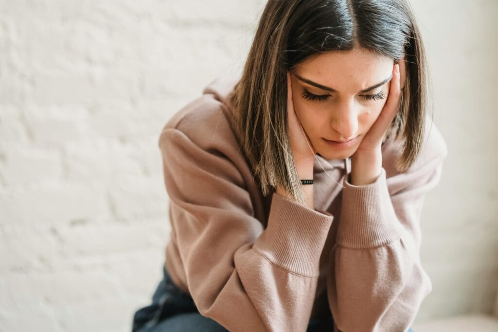 woman with head in hands sad