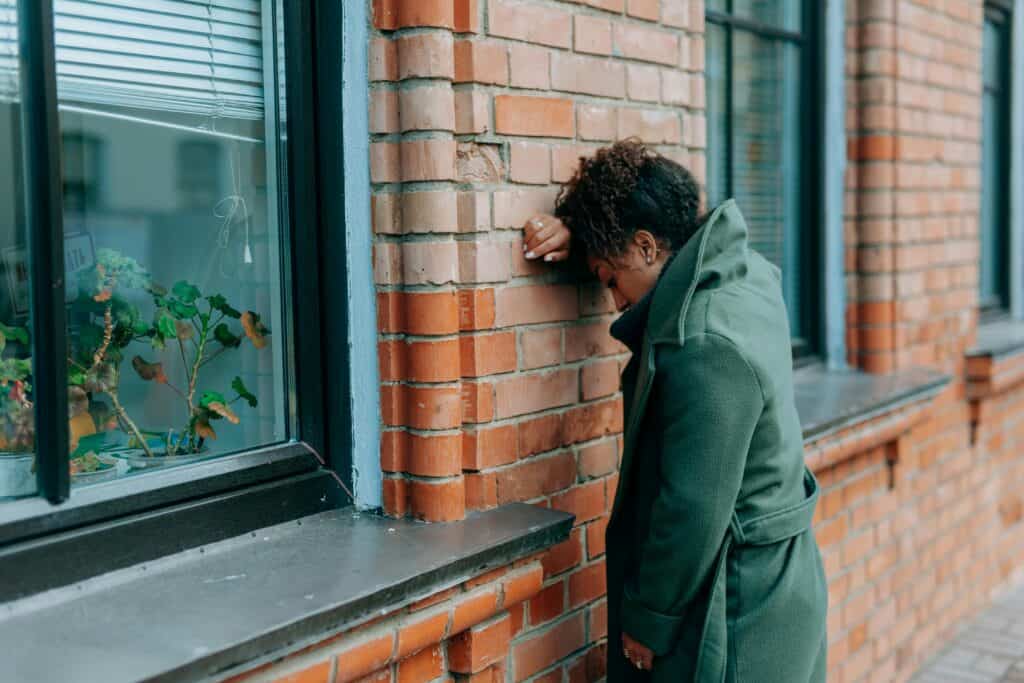 Woman sad leaning against building