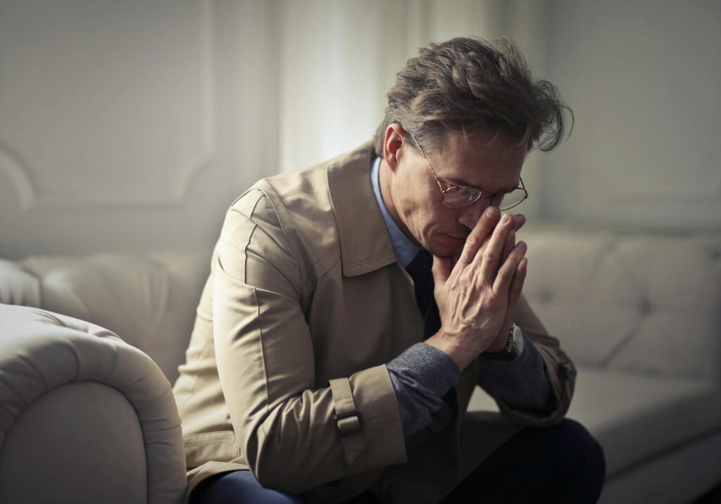 sad man head bowed hand in prayer pose