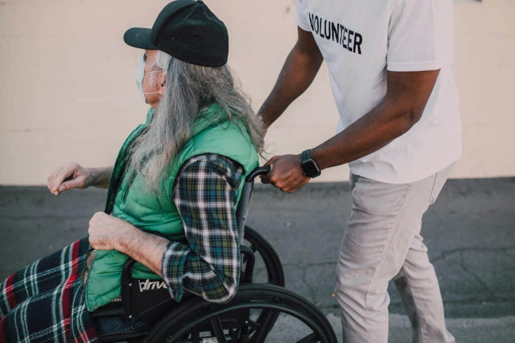 Man in volunteer shirt pushing older man in wheelchair