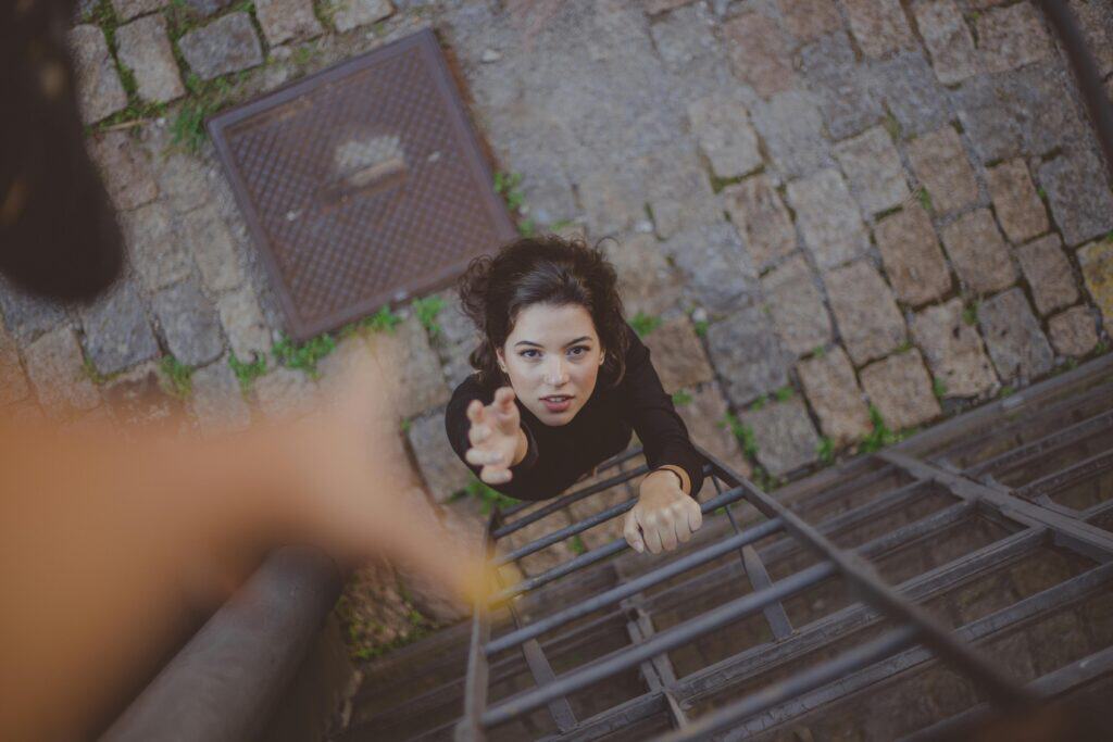 woman at bottom of ladder hand reaching out to help her up