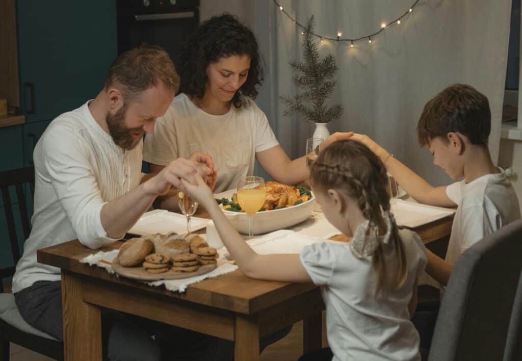 family holding hands praying at dinner table