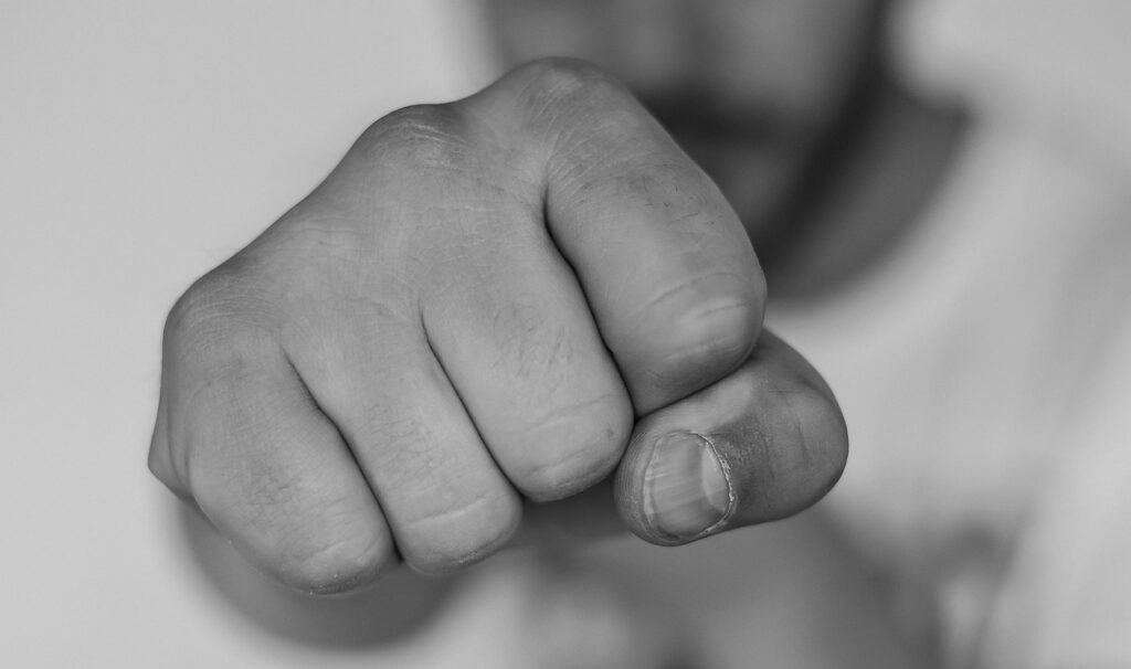 fist pointing at camera with man in background