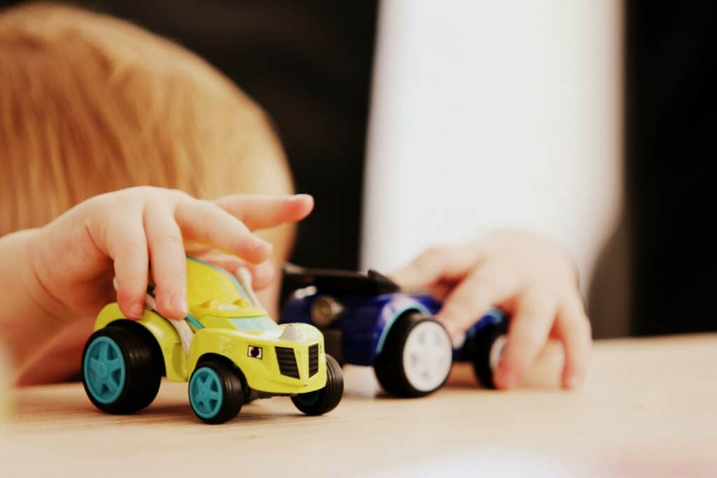 toddler hands driving two toy cars on table