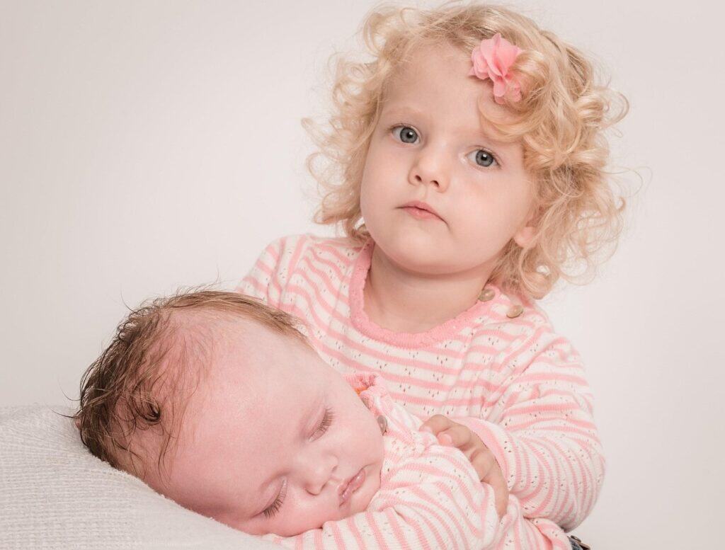Toddler frowning posed with baby sibling