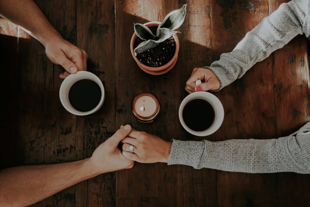 couple's hands holding hands and coffee cups