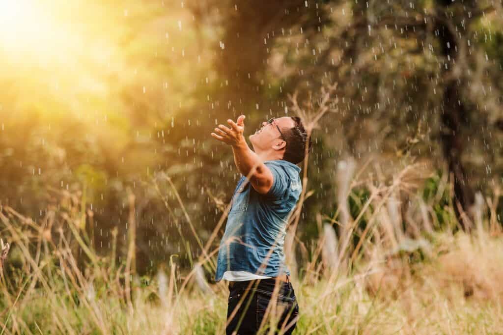 man lifting hands in a sunlit field