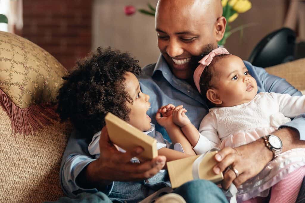 Father laughs with young son and baby daughter