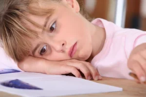 Homework battles. Sad Little girl with her head down on her schoolwork.