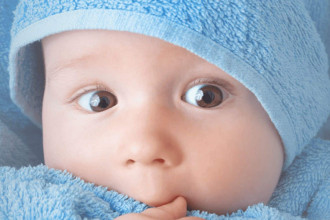 Bright-eyed newborn wrapped in a blue towel