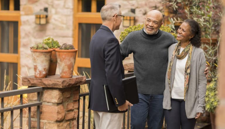 Grandfather and grandmother talk with their estate planner on a porch