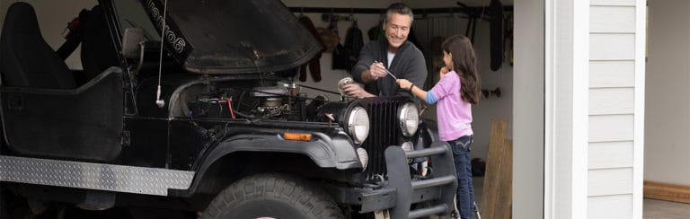 Grandfather and granddaughter repairing a car together