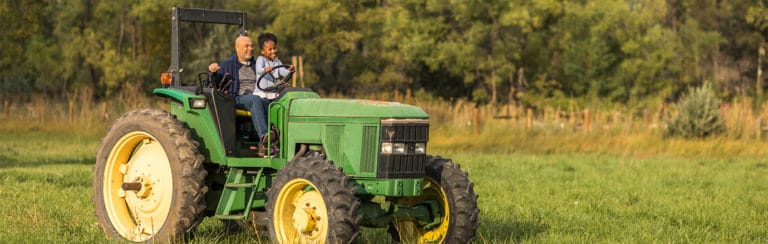 Daughter and grandfather riding in a tractor
