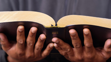 Man's hands holding out the bible and reading the word.