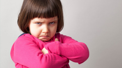 angry toddler crosses her arms