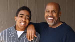 a father and teen son smile for a photo