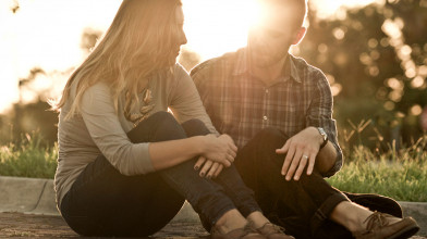 Married couple sitting outside, having a serious conversation