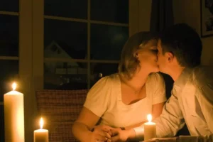 A couple sharing a kiss at a candlelit dinner table, symbolizing the essence of true romance in an intimate and serene setting.