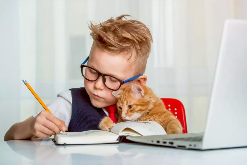 Helped by a cat, a young boy does his homework responsibilities