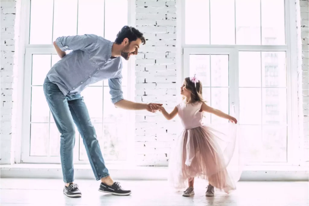 Building character in your princess. Daddy bowing to his little girl as he begins dancing with his daughter dressed in a pretty pink princess dress.