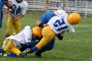 Teen football players tackling for the ball