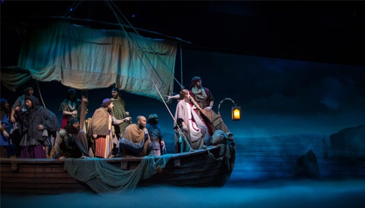 A group of actors stand on a boat reenacting a biblical scene