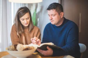 Couple reading the Bible and praying together at home.