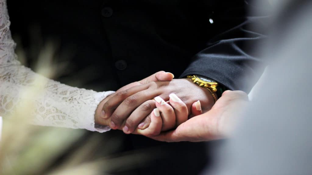 a man and woman hold hands during a wedding