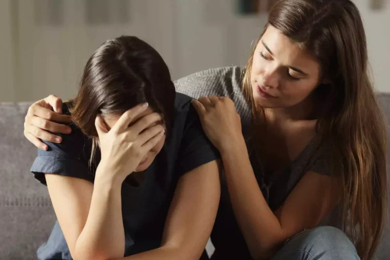 concerned woman comforts a distressed friend who has her head in her hands, symbolizing how to help someone in an abusive relationship.