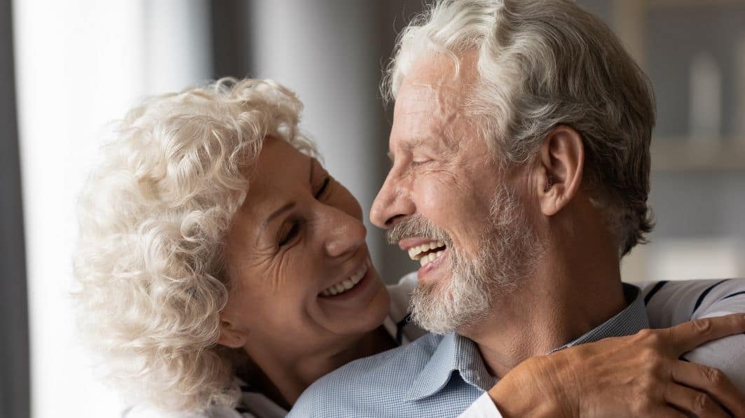an older man hugging a woman and laughing