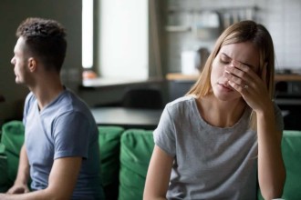 Upset married couple sitting, facing away from each other on a couch