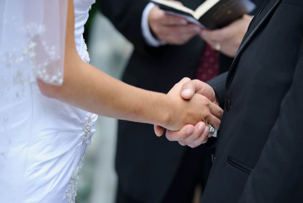 Photo of a married couple holding hands at a wedding ceremony