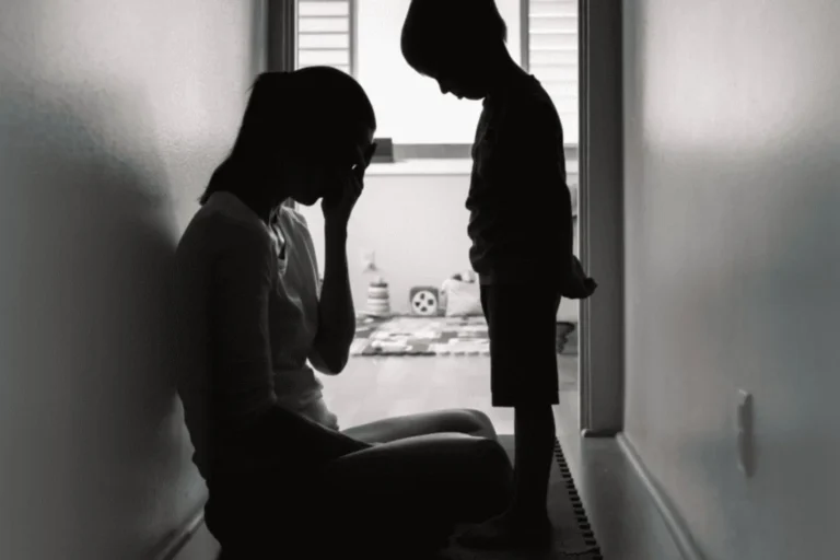Mom sitting on floor in hallway, crying while child looks on