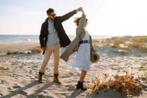 A husband twirling his wife as they dance on the beach to rekindle their relationship.