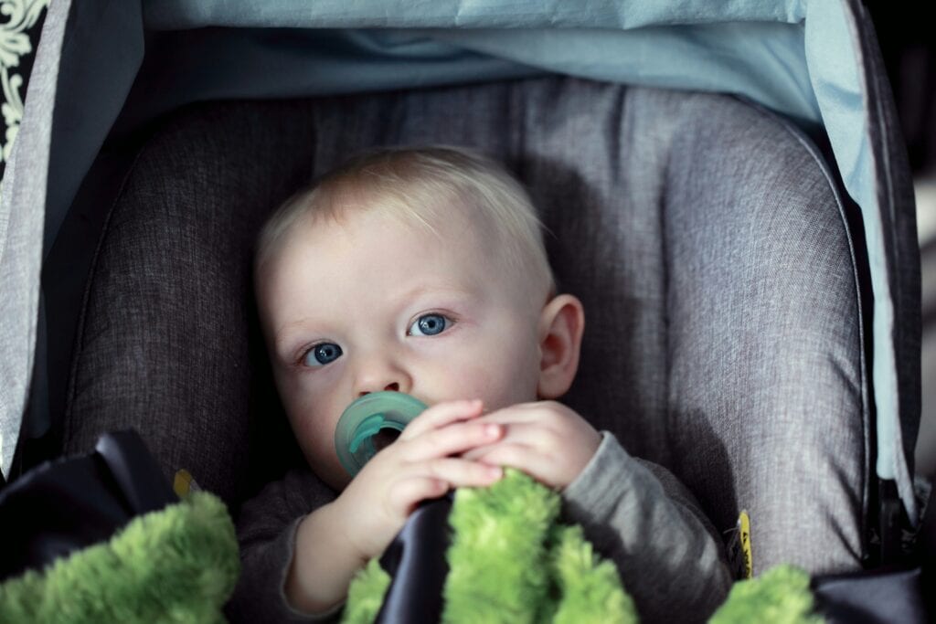 baby with pacifier in car seat