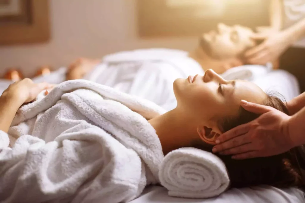 A husband and wife lying on their backs on massage tables, enjoying a relaxing self-care session, one of many self-care ideas they enjoy..