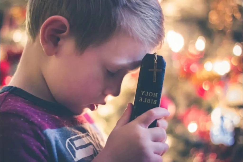 Young boy holding the Bible to his forehead as he prays