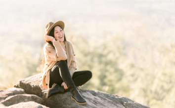 help others find hope - a teen girl sitting on a large boulder in a blurred field