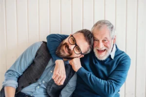 Father and adult son smiling and embracing each other, representing the positive aspects of adult children living at home.