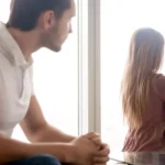 A photo of a man looking apologetically at a woman, whose back is turned. He is longing for forgiveness.