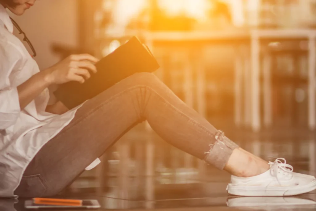 Teen sitting by a window reading a Bible, reflecting on how to get closer to God through quiet time and devotion.