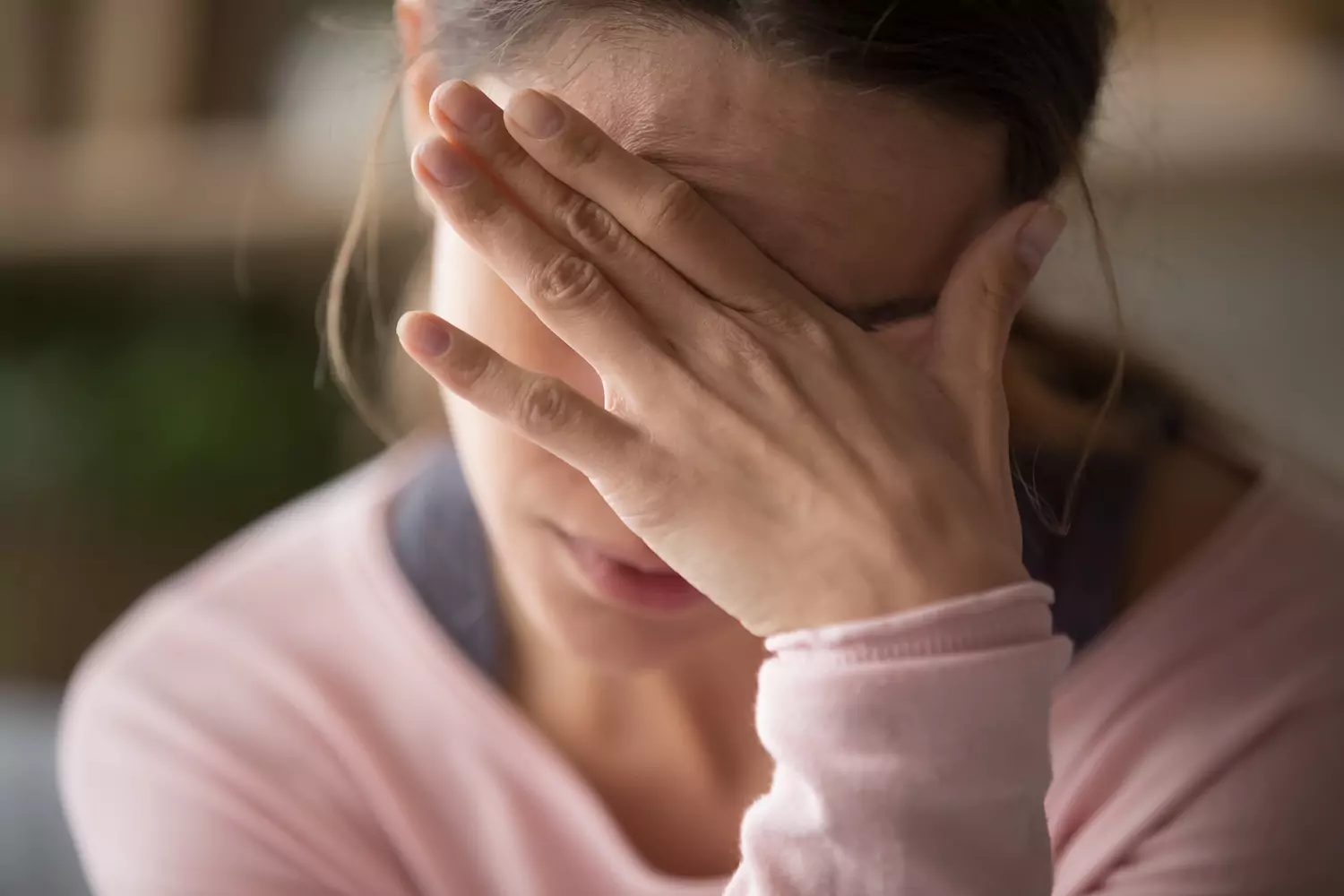 A photo of a stressed out woman holding her head in her hands. A wife may deal with unique mental burdens.