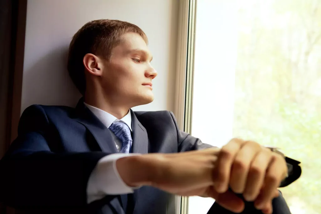A young groom sits near a window contemplating his future. Don't completely ignore wedding day second thoughts.