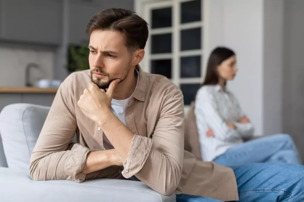 A man and a woman sit on opposite ends of a couch, turned away from each other. Here's how to identify and deal with a spouse on the autism spectrum.