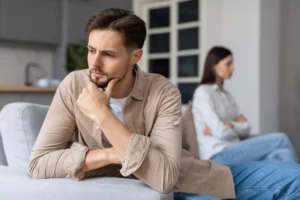 A man and a woman sit on opposite ends of a couch, turned away from each other. Here's how to identify and deal with a spouse on the autism spectrum.