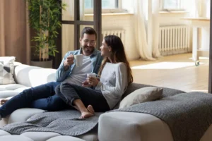 A couple sits on a couch in agreeable conversation while sitting close and drinking some coffee. These six marriage communication tools will help you build a solid foundation in your relationship.