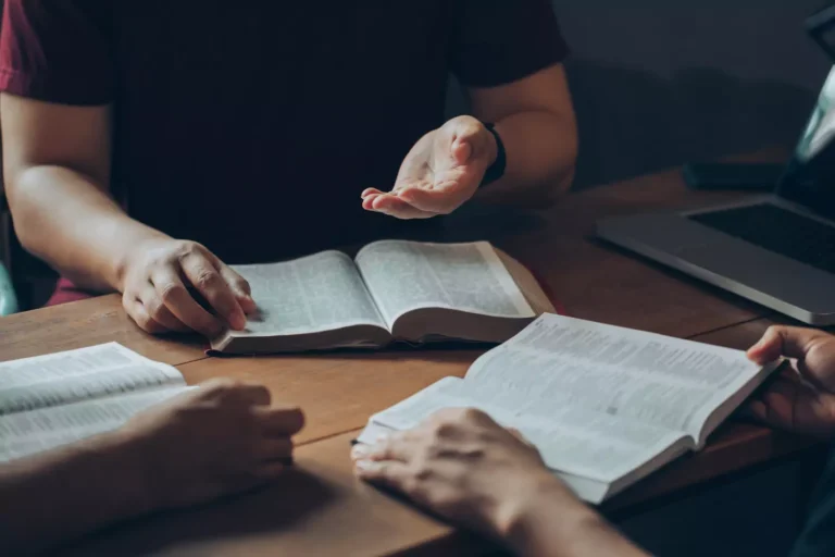Three people are sitting at a table with their bibles open in study. Gay Activist have used revisionist theology to argue their points. But what did God really say?