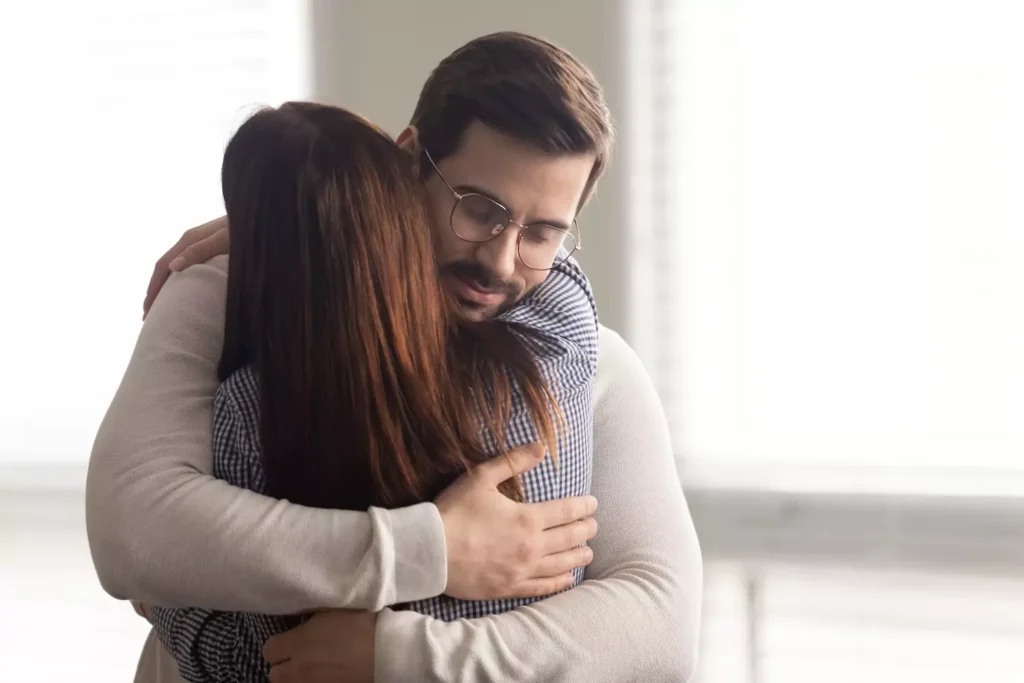 A husband hugs his wife tenderly and empathetically. Here are five ways to support your spouse after a job loss.