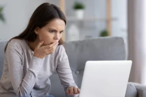 Young woman upset looking at her laptop screen seeing that her daughter is being cyberbullying