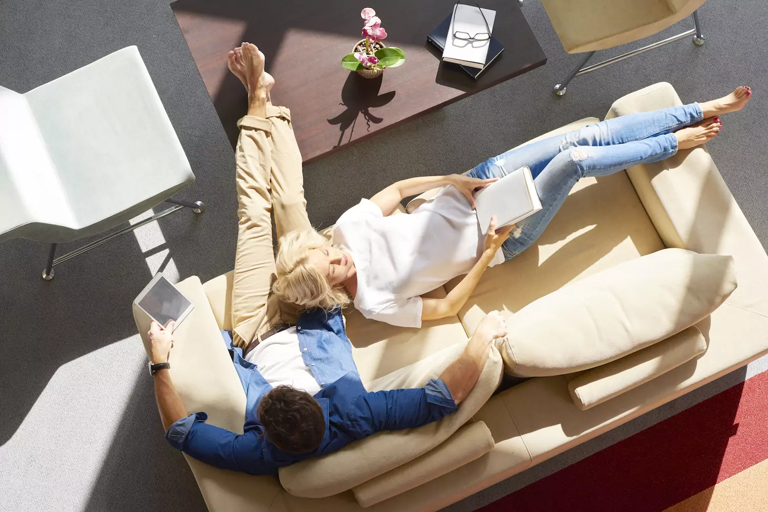 A married couple sits together on a couch reading books, with the woman lying her head down on her husband's lap. You can encourage connection and conflict resolution by suggesting Christian marriage books to someone who’s struggling in their marriage.